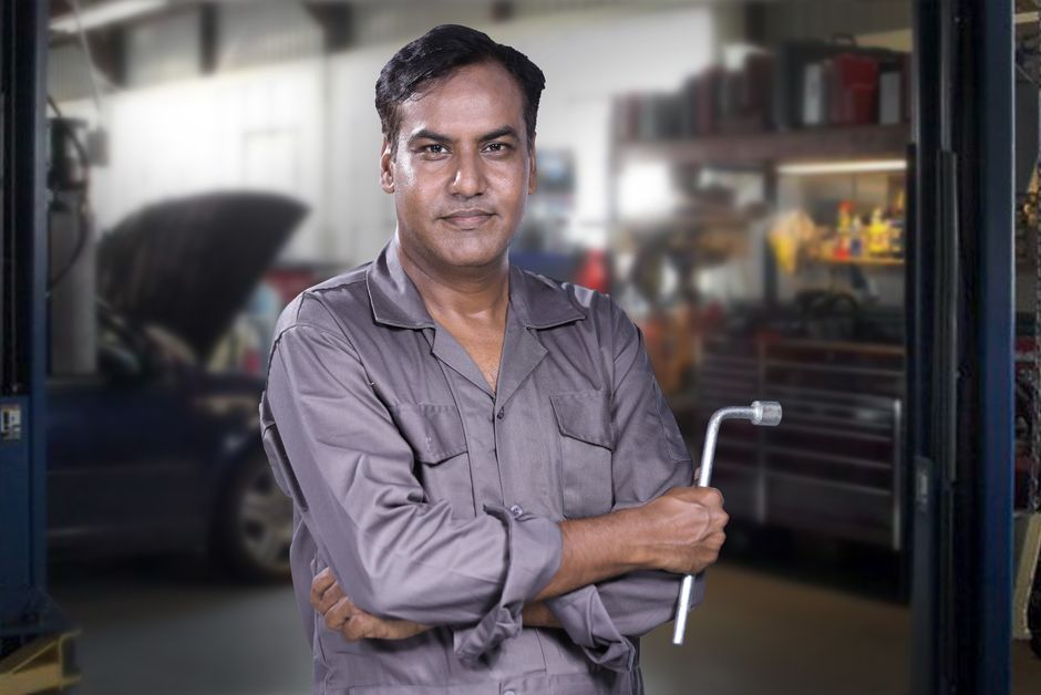 Smiling auto mechanic standing in a tire shop